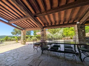 Portico in pietra con travi a vista e tavolo da pranzo, vista su giardino e colline — Poggio al Coniglio, villa a Suvereto (Toscana)
