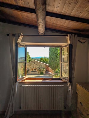Finestra aperta con vista su casale in pietra, cipresso e colline toscane — Poggio al Coniglio, Suvereto